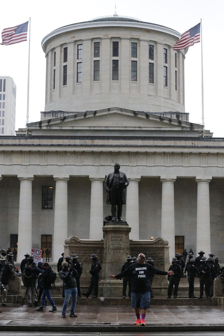 John Drury, of Hamilton, dances for peace in front of the Ohio Statehouse Sunday, Jan. 17, 2021, in Columbus, Ohio. Security was stepped up at statehouses across the U.S. after FBI warnings of potential armed protests at all 50 state capitols and in Washington, D.C. (AP Photo/Jay LaPrete)