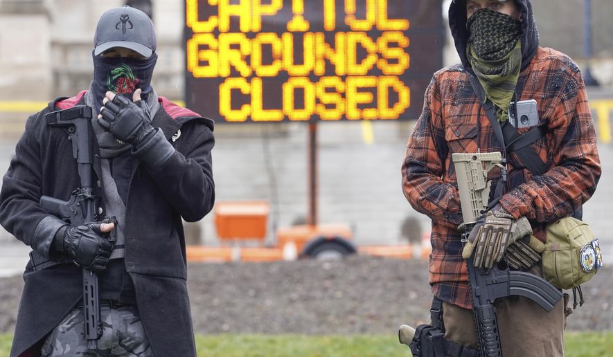 Members of the Boogaloo Boys, holding semi-automatic weapons stand outside at the Capitol building in Frankfort, Ky., Wednesday, Jan 17, 2021. The Capitol, the Capitol complex, and surrounding grounds have been closed. (AP Photo/Bryan Woolston)