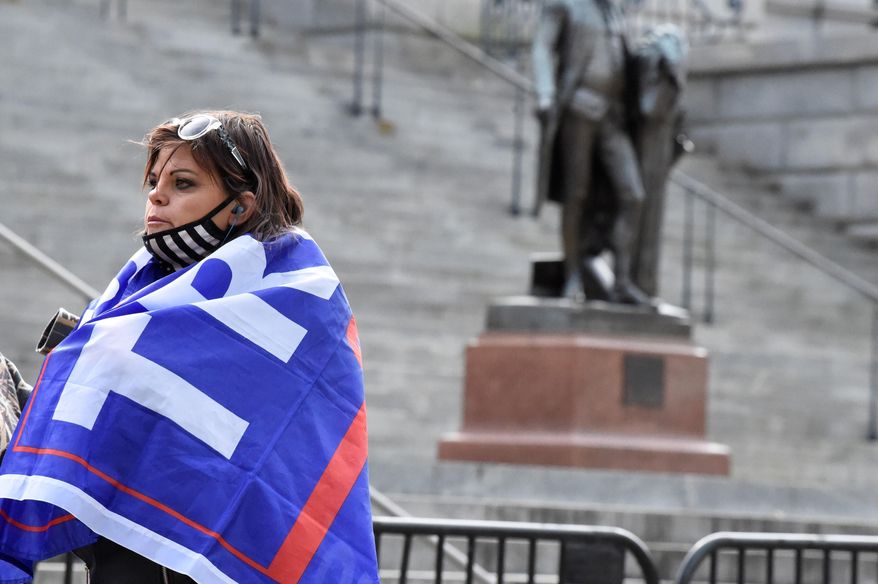 A woman with a Trump flag draped around her shoulders stands near a blocked off statue of George Washington at South Carolina&#x27;s Statehouse on Sunday, Jan. 17, 2021, in Columbia, S.C. Law enforcement has been stepped up at state capitols across the country during an expected week of unrest surrounding President-elect Joe Biden&#x27;s inauguration. (AP Photo/Meg Kinnard) **FILE**