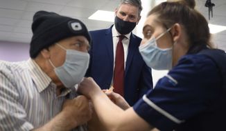 Britain&#x27;s Labour leader Sir Keir Starmer watches as Melvin Allanson receives the first of two COVID-19 vaccination shots during a visit to the vaccination centre at Robertson House, in Stevenage, England, Thursday, Jan. 14, 2021. (Leon Neal/Pool Photo via AP)