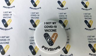 Stickers and a button given to people who receive their COVID-19 vaccines are displayed Thursday, Jan. 14, 2021, at the National Guard Armory in Charleston, W.Va. West Virginia has emerged an unlikely success in the nation&#39;s otherwise chaotic vaccine rollout. (AP Photo/John Raby)