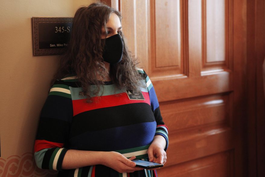In this photo from Friday, Jan. 15, 2021, Rachel Sweet, a lobbyist for Planned Parenthood Great Plains, watches a legislative committee hearing on a proposed anti-abortion amendment to the state constitution in a hallway just outside the meeting room at the Statehouse in Topeka, Kan. The proposed amendment would overturn a 2019 Kansas Supreme Court decision declaring access to abortion a "fundamental" right under the state constitution. (AP Photo/John Hanna)
