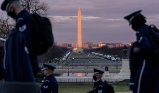 The Washington Monument and the National Mall are visible as members of the U.S. Air Force Honor Guard walk along the West Front of the U.S. Capitol at the site of the 59th Presidential Inauguration in Washington, Monday, Jan. 18, 2021. (AP Photo/Andrew Harnik)