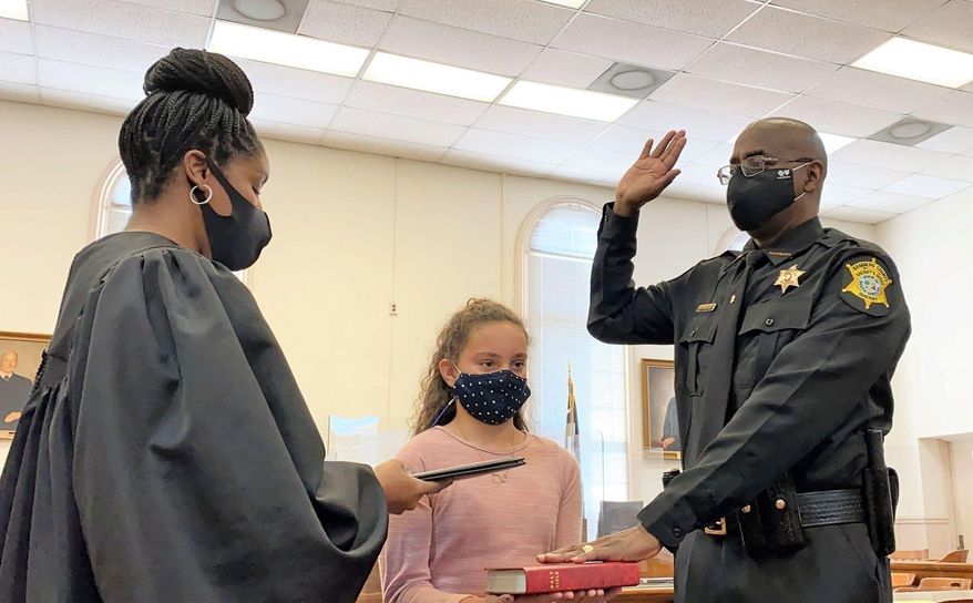 Circuit Judge Clyburn Pope administers the oath of office to Bamberg County Sheriff Kenny Bamberg, the rural South Carolina county's first Black sheriff, as his granddaughter Aubree Bamberg holds the Bible on Tuesday, Jan. 5, 2021, at the Bamberg County Courthouse in Bamberg, S.C. (Martha Rose Brown/The Times and Democrat via AP)