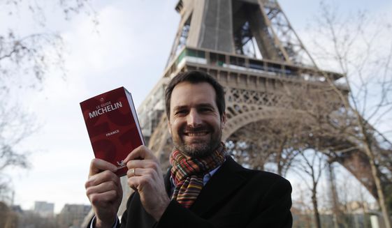 Gwendal Poullennec, head of Le Guide Michelin, poses outside the Eiffel Tower with the 2021 edition Monday, Jan. 18, 2021 in Paris. Michelin will later announce the 2021 winners in a broadcast from the Eiffel Tower. (AP Photo/Francois Mori)