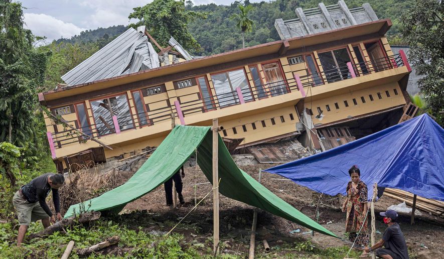 Residents build tents outside their house badly damaged by earthquake in Mamuju, West Sulawesi, Indonesia, Tuesday, Jan. 19, 2021. Aid was reaching the thousands of people left homeless and struggling after an earthquake that killed a number of people struck early Friday. (AP Photo/Yusuf Wahil)
