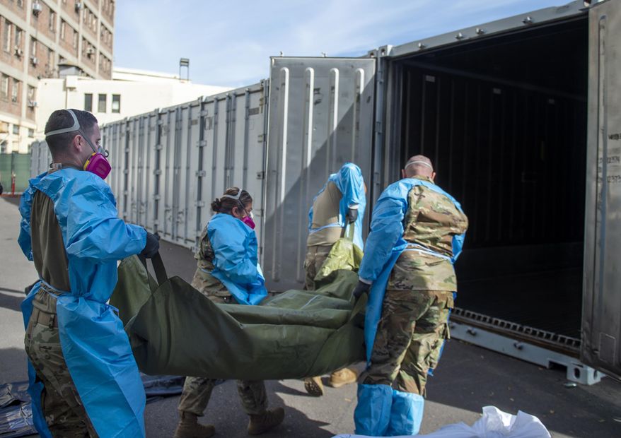 FILE - In this Jan. 12, 2021 photo provided by the Los Angeles County Department of Medical Examiner-Coroner, National Guard members assisting with processing COVID-19 deaths, placing them into temporary storage at the medical examiner-coroner's office in Los Angeles. The seven-day rolling average of daily deaths is rising in 30 states and the District of Columbia, and on Monday, Jan 18, 2021, the U.S. was approaching 398,000, according to data collected by Johns Hopkins University, by far the highest of any country in the world. (Los Angeles County Department of Medical Examiner-Coroner via AP, File)