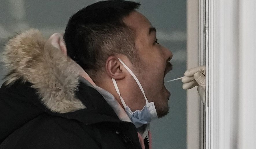 A man gets a swab for the coronavirus test at a hospital in Beijing, Sunday, Jan. 17, 2021. The coronavirus was found on ice cream produced in eastern China, prompting a recall of cartons from the same batch, according to the government. (AP Photo/Andy Wong)