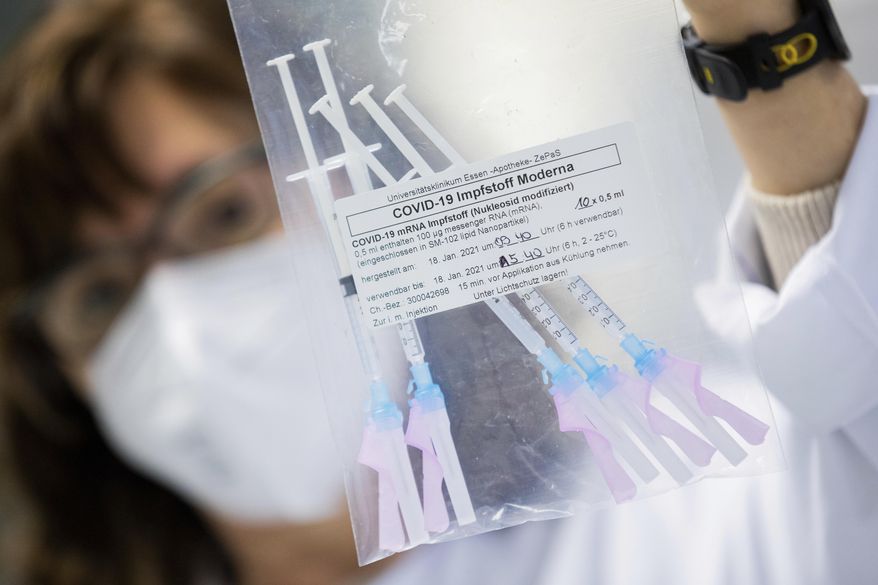 A healthcare worker shows a bag of syringes containing the Moderna new coronavirus vaccine immediately before a vaccination at the University Hospital in Essen, Germany, Monday, Jan. 18, 2021. The Corona vaccination campaign in the German state of North Rhine-Westphalia has been extended to hospital staff. (Rolf Vennenbernd/dpa via AP)