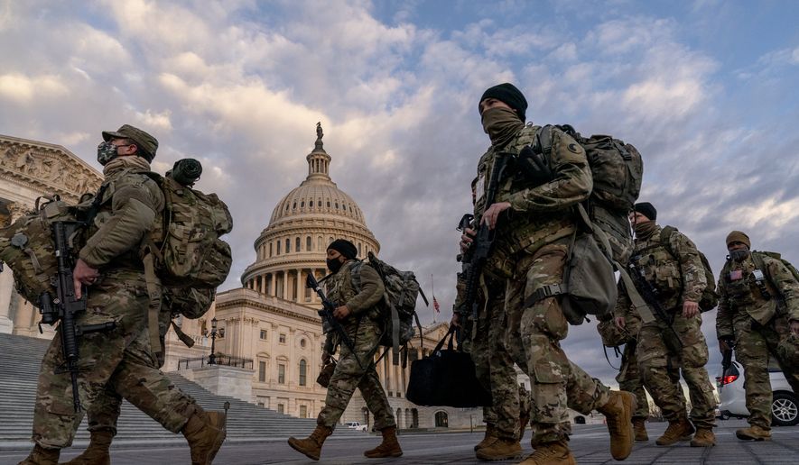 Armed National Guard troops walk past the U.S. Capitol two days before the 59th Presidential Inauguration in Washington, Monday, Jan. 18, 2021. (AP Photo/Andrew Harnik)