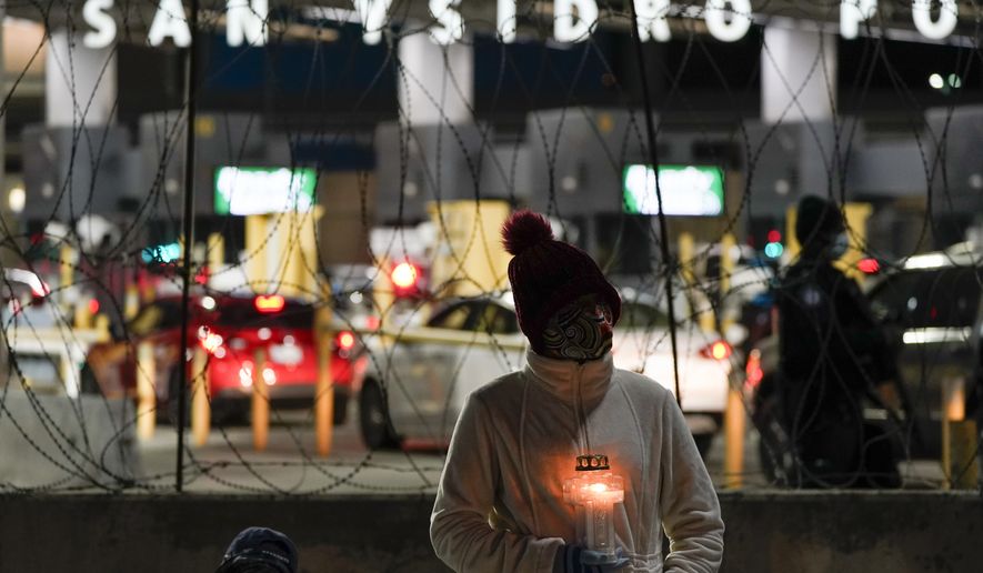 A woman holds a candle during a vigil in support of migrants as she stands at the entrance to the San Ysidro Port of Entry along the border between the United States and Mexico, late Tuesday, Jan. 19, 2021, in Tijuana, Mexico. President-elect Joe Biden plans to unveil a sweeping immigration bill on Day One of his administration. It would provide an eight-year path to citizenship for an estimated 11 million people living in the U.S. without legal status, according to a person granted anonymity to discuss the legislation. (AP Photo/Gregory Bull)