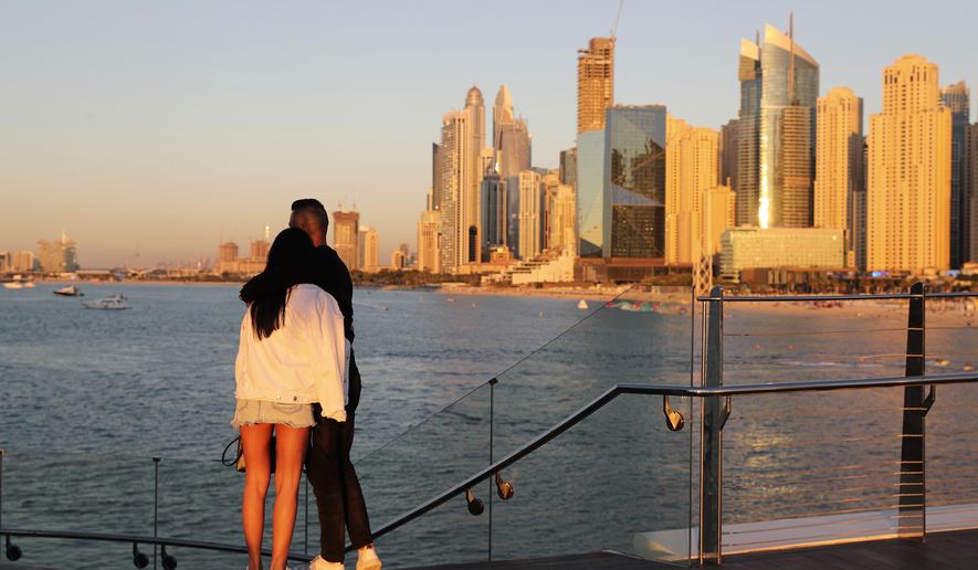 Tourists look at the skyline at sunset, in Dubai, United Arab Emirates, Tuesday, Jan. 12, 2021. Since becoming one of the world&#x27;s first destinations to open up for tourism, Dubai has promoted itself as the ideal pandemic vacation spot. With peak tourism season in full swing, coronavirus infections are surging to unprecedented heights, with daily case counts nearly tripling in the past month, but in the face of a growing economic crisis, the city won&#x27;t lock down and can&#x27;t afford to stand still. (AP Photo/Kamran Jebreili)