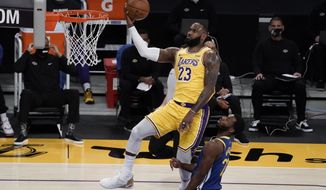 Los Angeles Lakers&#39; LeBron James, top, goes up for a basket as Golden State Warriors&#39; Andrew Wiggins watches during the first half of an NBA basketball game, Monday, Jan. 18, 2021, in Los Angeles. (AP Photo/Jae C. Hong)
