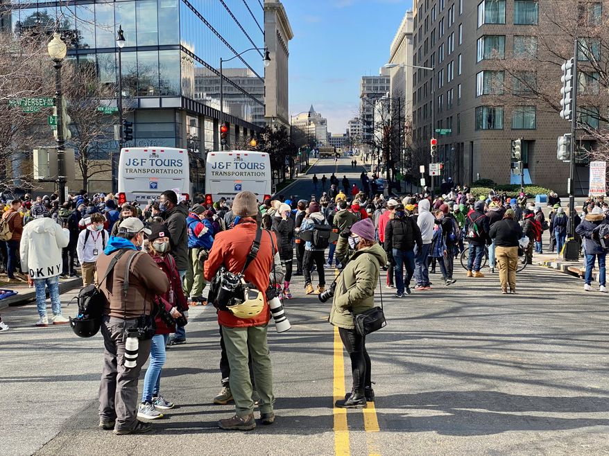People gathered around two tour buses parked near the U.S. Capitol at the northwest intersection of New Jersey Avenue and D Street shortly after President Biden was sworn in on Wednesday. (Emily Zantow/ The Washington Times)