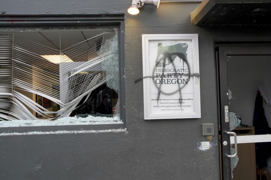 Protesters tag and smash windows at the Democratic Party of Oregon headquarters during the J20 March, Wednesday, Jan. 20, 2021, in Southeast Portland. A group of protesters carrying anti-President Joe Biden and anti-police signs marched in the streets and damaged the headquarters of the Democratic Party of Oregon.  (Beth Nakamura/The Oregonian via AP)