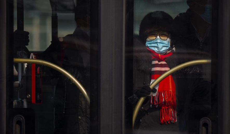A woman wearing a face mask to protect against the spread of the coronavirus rides a public bus in Beijing, Wednesday, Jan. 20, 2021. China is now dealing with coronavirus outbreaks across its frigid northeast, prompting additional lockdowns and travel bans. (AP Photo/Mark Schiefelbein)