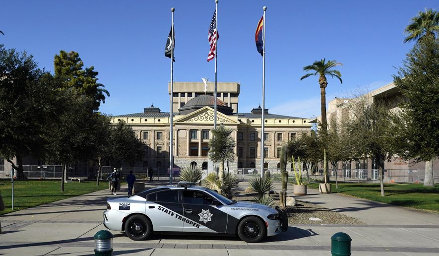 An Arizona State Trooper vehicle drives in front of the Arizona Capitol Wednesday, Jan. 20, 2021, in Phoenix. (AP Photo/Ross D. Franklin)