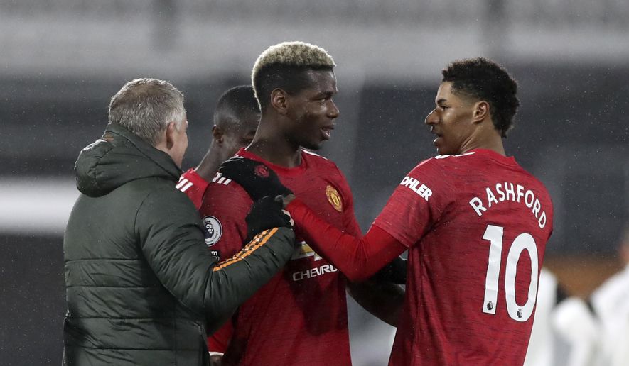 Manchester United&#39;s Paul Pogba, centre, celebrates with Manchester United&#39;s manager Ole Gunnar Solskjaer, left, and Manchester United&#39;s Marcus Rashford at the end of the English Premier League soccer match between Fulham and Manchester United at the Craven Cottage stadium in London, Wednesday, Jan. 20, 2021. (Peter Cziborra/Pool via AP)