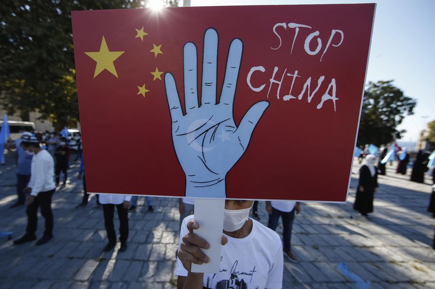 In this file photo taken Thursday, Oct. 1, 2020, a protester from the Uighur community living in Turkey, holds an anti-China placard during a protest in Istanbul against what they allege is oppression by the Chinese government to Muslim Uighurs in far-western Xinjiang province. The accusation of genocide by U.S. Secretary of State Mike Pompeo against China touches on a hot-button human rights issue between China and the West. (AP Photo/Emrah Gurel, File)