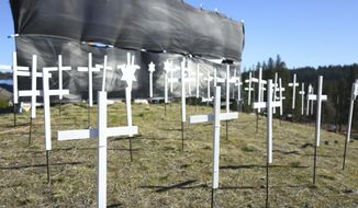 The 73 crosses signifying COVID-19 deaths in Nevada County, sit on the hill next to Old Barn Storage Tuesday, Jan. 19, 2021 in Grass Valley, Calif. (Elias Funez/The Union via AP)