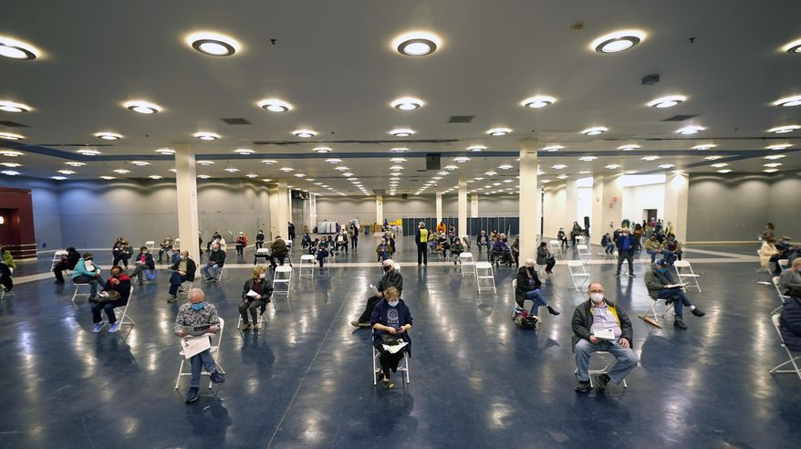 People that received a COVID-19 vaccine socially distance as they wait the required fifteen minutes to monitor for adverse reactions after getting the shot at the Dallas County mass vaccination site at Fair Park Wednesday, Jan. 20, 2021, in Dallas. (AP Photo/LM Otero)