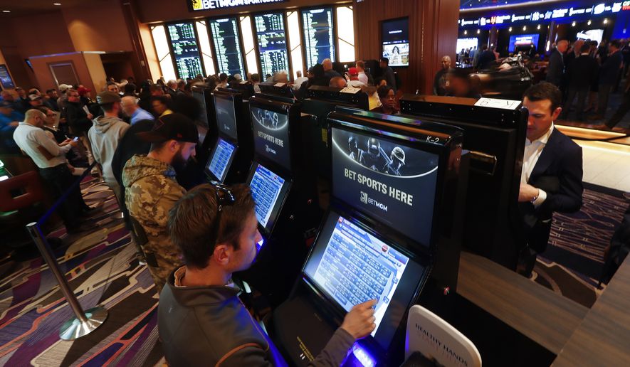FILE - In this March 11, 2020, file photo, patrons place in person bets during the launch of legalized sports betting in Michigan at the MGM Grand Detroit casino in Detroit. Online sports betting and casino games will start in Michigan at noon Friday, Jan. 22, 2021, an expansion of options for gamblers who now wager through offshore sites. State regulators have authorized licenses for all three Detroit casinos and seven of the dozen tribes with &quot;Class III&quot; casinos. (AP Photo/Paul Sancya, File)
