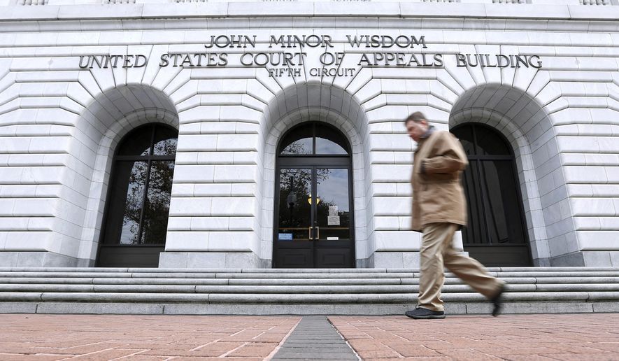 FILE - In this Jan. 7, 2015, file photo, a man walks in front of the 5th U.S. Circuit Court of Appeals in New Orleans. Texas should be allowed to halt a common second-trimester abortion procedure, the state's lawyers told a federal appeals court Thursday, Jan. 21, 2021, in a hearing punctuated by debates over fetal pain and the rights of women to medically safe abortion. (AP Photo/Jonathan Bachman, File)