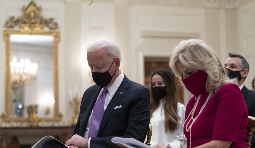 President Joe Biden bows his head in prayer, during a virtual Presidential Inaugural Prayer Service, accompanied by first lady Jill Biden, second from right, in the State Dinning Room of the White House, Thursday, Jan. 21, 2021, in Washington. (AP Photo/Alex Brandon)