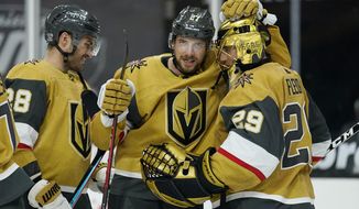Vegas Golden Knights defenseman Shea Theodore (27) embraces goaltender Marc-Andre Fleury (29) after defeating the Arizona Coyotes in an NHL hockey game Wednesday, Jan. 20, 2021, in Las Vegas. (AP Photo/John Locher)
