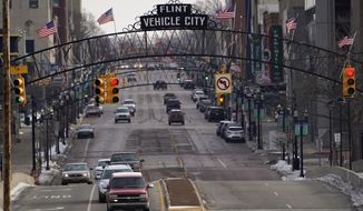 FILE - In this Jan. 13, 2021 file photo, vehicles drive through downtown Flint, Mich. A judge granted preliminary approval Thursday, Jan. 21, 2021, to a $641 million deal that would benefit Flint residents who were harmed by lead-contaminated water. The settlement includes $600 million from the state of Michigan, although Flint, an area hospital and an engineering firm are also part of the agreement. (AP Photo/Paul Sancya File)