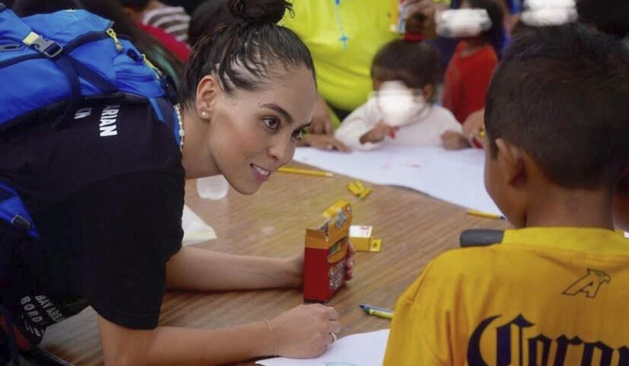 In this October 2019 photo provided by Pocho Sanchez, Daniela Dominguez, assistant professor in counseling psychology at University of San Francisco, draws and chats with children from Honduras at a migrant camp in Matamoros, Mexico. Dominguez said mutual aid networks are part of the Latino culture where people may feel safer getting help from their own community rather than government entities or formal charities. (Pocho Sanchez via AP)