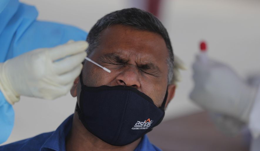 Sri Lankan municipal health workers take a swab sample from a man to test for COVID-19 in Colombo, Sri Lanka, Thursday, Jan. 21, 2021. Sri Lanka on Thursday re-opened the country for tourists after keeping the doors closed for the visitors for nearly 10 months due to the COVID-19. (AP Photo/Eranga Jayawardena)