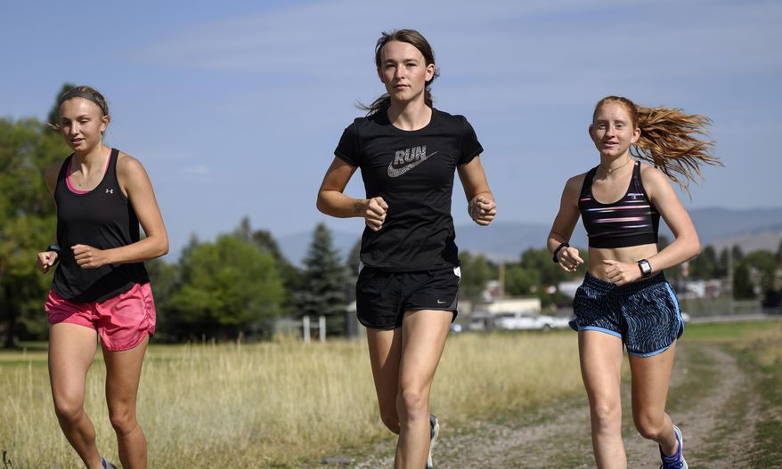 FILE - In this Aug. 15, 2019, file photo, is University of Montana cross country runner Juniper Eastwood, center, warming up with her teammates at Campbell Park in Missoula, Mont. Transgender kids would be banned from playing on school sports teams for the gender with which they identify under a GOP-backed bill that advanced Thursday, Jan. 21, 2021, in Montana. The proposed ban is personal for people like Eastwood, a transgender woman and former member of the University of Montana's track and field and cross-country running teams. She said the legislation "would make it impossible for other young Montanans like me to participate in sports as who they are." (Rachel Leathe/Bozeman Daily Chronicle via AP, file)