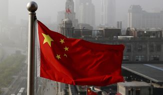 A Chinese national flag flutters against the office buildings in Shanghai, China. (AP Photo/Andy Wong) **FILE**