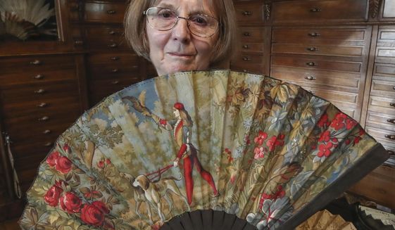 Anne Hoguet, 74, fan maker and director of the hand fan-making museum poses with a wood roasted hand fan representing a falcon hunt, gouache painting g on paper from 1880 at the museum in Paris, Wednesday, Jan. 20, 2021. Just like the leaves of its gilded fans, France&#39;s storied hand fan-making museum could fold up and vanish. The splendid Musee de l&#39;Eventail in Paris, a classed historical monument, is the culture world&#39;s latest coronavirus victim. (AP Photo/Michel Euler)