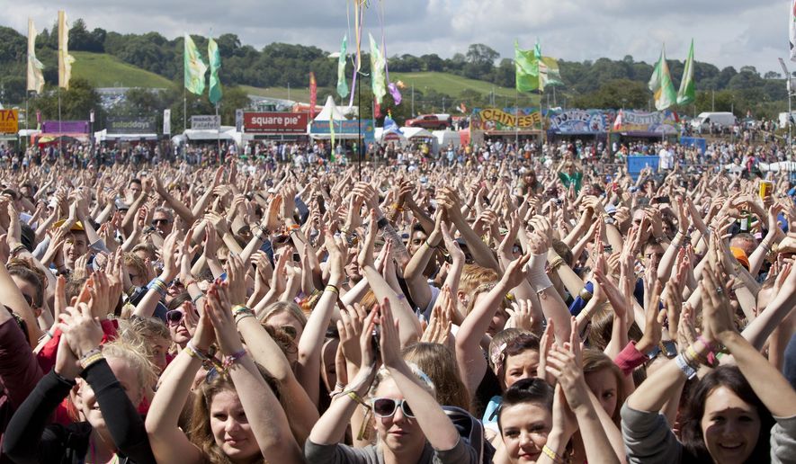 FILE - In this Friday, June 24, 2011 file photo, the crowd at Glastonbury Music Festival clap their hands above their heads as they watch Chipmunk on stage, Glastonbury, England. Britain’s Glastonbury music festival has fallen victim to the coronavirus pandemic for the second year in a row, organizers Michael Eavis and Emily Eavis said Thursday Jan. 21, 2021. (AP Photo/Joel Ryan, File)