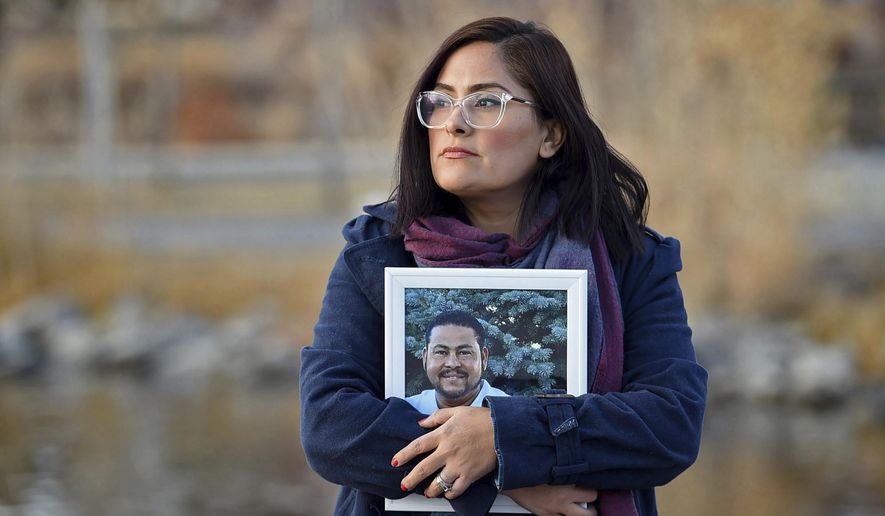 FILE - In this Dec. 15, 2020, file photo, Brenda Bravo Torres stands at a park in Reno, Nev., holding a photograph of her husband Miguel Angel Lopez Villal Pinzon who died of COVID-19 in August 2020. Nevada reported 71 new deaths from the coronavirus on Wednesday, Jan. 20, 2021, surpassing the highest single-day death toll, the 63 reported just last Saturday. (Andy Barron/The Reno Gazette-Journal via AP, File)