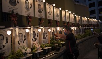 Javier Casana leaves flowers on the portrait of his uncle Jorge Luis Casana, 62, a doctor who died from COVID-19, in Lima, Peru, Tuesday, January 19, 2021. The Peruvian Medical College reported that at least 11 doctors have died during the first days of 2021. (AP Photo/Rodrigo Abd)
