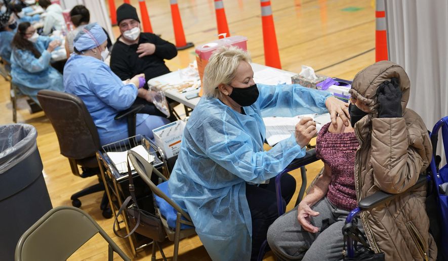 Miriam Palomino, right, received the COVID-19 vaccine in Paterson, N.J., Thursday, Jan. 21, 2021. The first people arrived around 2:30 a.m. for the chance to be vaccinated at one of the few sites that does not require an appointment. (AP Photo/Seth Wenig)