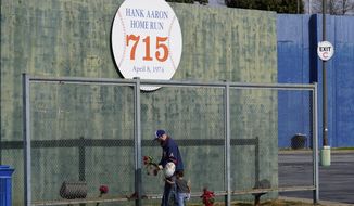 Les Motes and his two-year-old daughter Mahalia leave flowers, Friday, Jan. 22, 2021, in Atlanta, near the spot where a ball hit for a home run by Atlanta Braves&#39; Hank Aaron cleared the wall to break Babe Ruth&#39;s career home run record in 1974. Aaron, who endured racist threats with stoic dignity during his pursuit of Babe Ruth but went on to break the career home run record in the pre-steroids era, died peacefully in his sleep early Friday. He was 86. (AP Photo/John Bazemore)