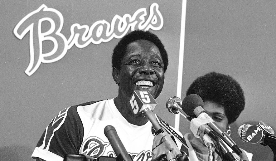 FILE - Atlanta Braves&#39; Hank Aaron smiles during a press conference at Atlanta Stadium, Ga., after the game in which he hit his 715th career home, in this April 8, 1974, file photo. With him is his wife Billye, partially obscured. Hank Aaron, who endured racist threats with stoic dignity during his pursuit of Babe Ruth’s home run record and gracefully left his mark as one of baseball’s greatest all-around players, died Friday. He was 86. The Atlanta Braves, Aaron&#39;s longtime team, said he died peacefully in his sleep. No cause was given. (AP Photo/File)