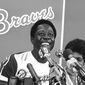 FILE - Atlanta Braves&#x27; Hank Aaron smiles during a press conference at Atlanta Stadium, Ga., after the game in which he hit his 715th career home, in this April 8, 1974, file photo. With him is his wife Billye, partially obscured. Hank Aaron, who endured racist threats with stoic dignity during his pursuit of Babe Ruth’s home run record and gracefully left his mark as one of baseball’s greatest all-around players, died Friday. He was 86. The Atlanta Braves, Aaron&#x27;s longtime team, said he died peacefully in his sleep. No cause was given. (AP Photo/File)