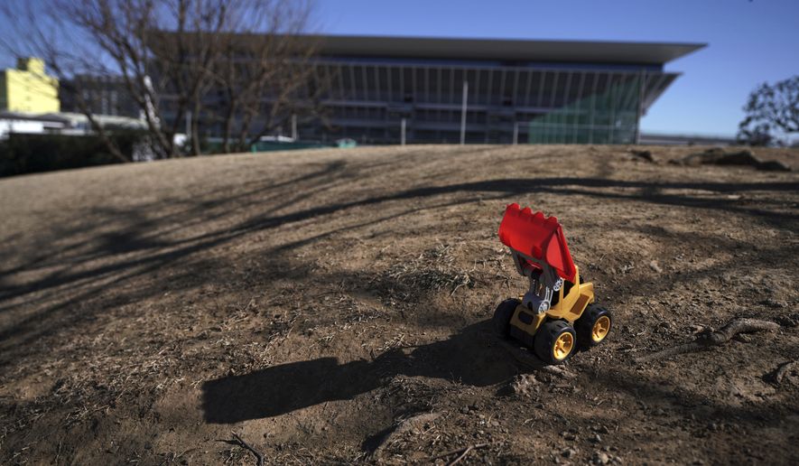 A leftover toy bulldoze is seen near the Tokyo Aquatics Center, one of the venues of Tokyo 2020 Olympic and Paralympic games, in Tokyo Wednesday, Jan. 20, 2021. The postponed Tokyo Olympics are to open in just six months. Local organizers and the International Olympic Committee say they will go ahead on July 23. But it’s still unclear how this will happen with virus cases surging in Tokyo and elsewhere around the globe. (AP Photo/Eugene Hoshiko)