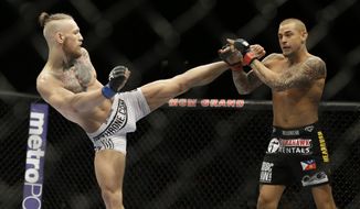 FILE - In this Sept. 27, 2014, file photo, Conor McGregor, left, kicks Dustin Poirier during their mixed martial arts bout in Las Vegas. McGregor returns from a year-long layoff for a rematch against Poirier in the promotions&#39;s first pay-per-view of the year, at UFC 257 on Jan. 24 at Abu Dhabi. (AP Photo/John Locher, File)