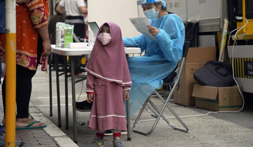Residents wearing face masks to protect against the spread of the coronavirus, queue at a temporary testing center for COVID-19, in Hong Kong, Friday, Jan. 22, 2021. Hong Kong's Yau Ma Tei area is expected to be put into lockdown due to the rising number of coronavirus cases. The territory has reported 9,797 positive cases and 166 deaths to date, according to Johns Hopkins University. (AP Photo/Kin Cheung)