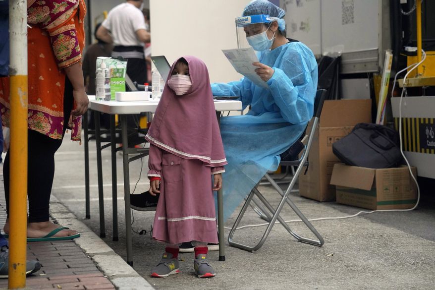 Residents wearing face masks to protect against the spread of the coronavirus, queue at a temporary testing center for COVID-19, in Hong Kong, Friday, Jan. 22, 2021. Hong Kong's Yau Ma Tei area is expected to be put into lockdown due to the rising number of coronavirus cases. The territory has reported 9,797 positive cases and 166 deaths to date, according to Johns Hopkins University. (AP Photo/Kin Cheung)