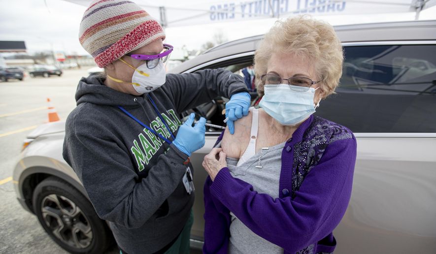 Joanna Rolfe of Ona, right, receives a COVID-19 vaccine from Marshall University student nurse Angie Bush, left, as health care workers with the Cabell County EMS and Cabell-Huntington Health Department administer vaccines during a drive-thru clinic on Thursday, Jan. 21, 2021, outside of the St. Mary&#x27;s School of Nursing in Huntington, WVa. (Sholten Singer/The Herald-Dispatch via AP)