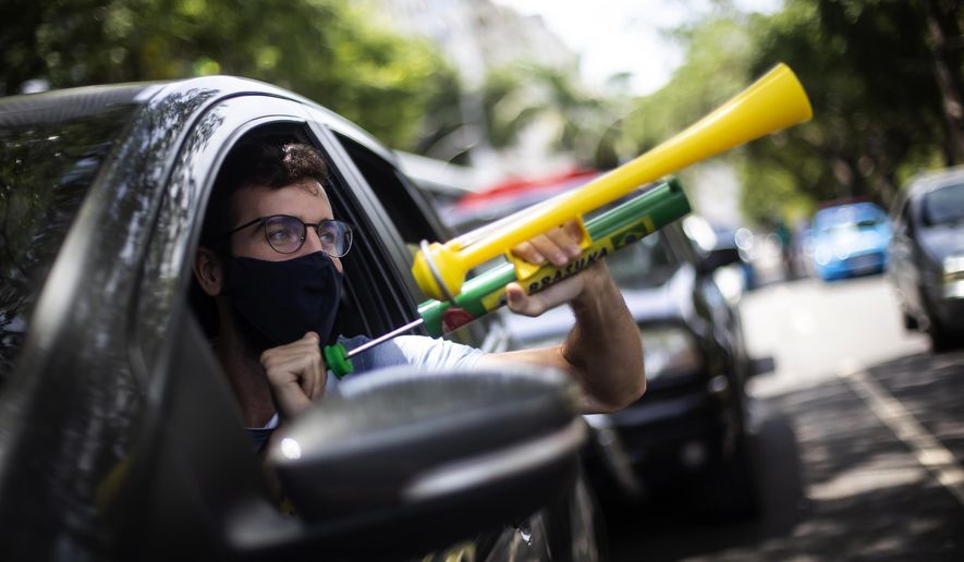 A demonstrator shouts &amp;quot;Out Bolsonaro&amp;quot; while using a noisemaker during a caravan to protest the government&#x27;s handling of the COVID-19 pandemic and demand the impeachment of Brazilian President Jair Bolsonaro in Rio de Janeiro, Brazil, Saturday, Jan. 23, 2021. (AP Photo/Bruna Prado)