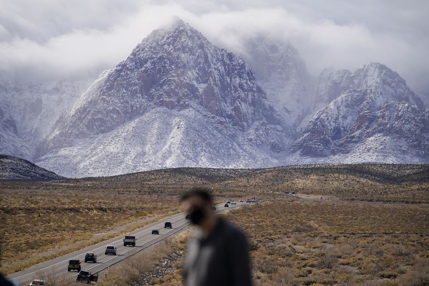 People look at mountains recently covered with snow, Monday, Jan. 25, 2021, at the Red Rock National Conservation Area near Las Vegas. (AP Photo/John Locher)