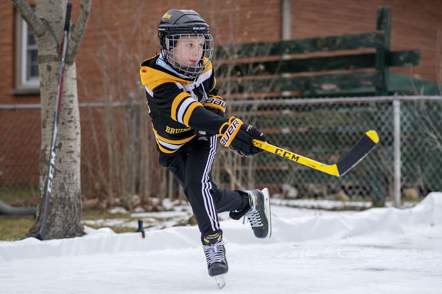 Bronson Jones, 10, practices hockey in his backyard on Monday, Jan. 11, 2021 in Battle Creek, Mich. The backyard ice rink was constructed by his father, Justin Jones. (Alyssa Keown /Battle Creek Enquirer via AP)